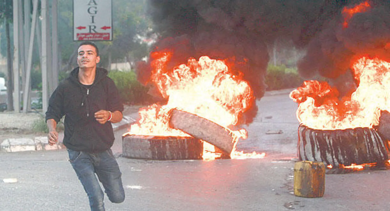 شاب فلسطيني يركض هربا من ملاحقة قوات الأمن الإسرائيلية بعد حدوث مواجهات بين فلسطينيين وقوات اسرائيلية في الضفة الغربية أمس (أ.ب)