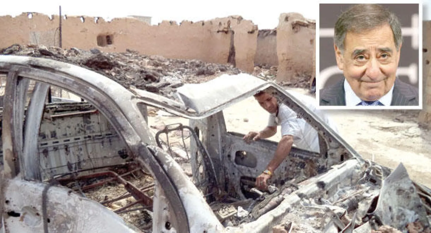 ليون بانيتا  و عراقي يتفحص بقايا سيارة بعد تفجيرها من قبل تنظيم {داعش} في تكريت شمال العراق (إ.ب.أ)