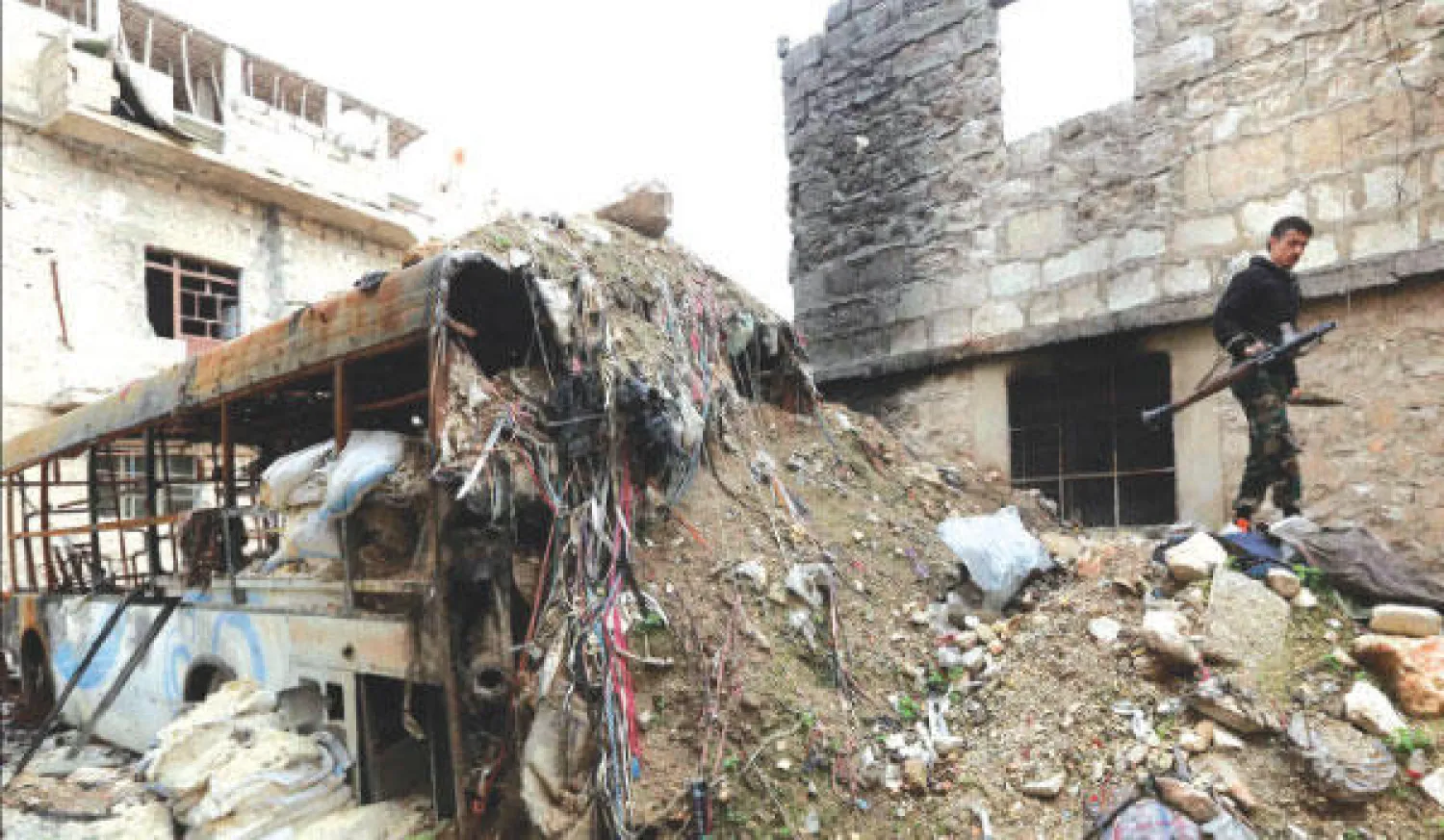 مقاتل من الجيش السوري الحر يمر فوق ركام مبنى في منطقة الأشرفية بحلب أمس (رويترز).