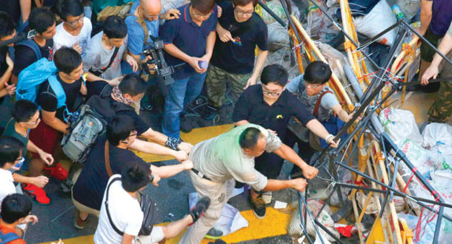 حشد من الناس يمنعون رجلا أراد إزالة حواجز أقامها المتظاهرون المطالبون بالديمقراطية في حي مونغ كوك التجاري بهونغ كونغ أمس (رويترز)