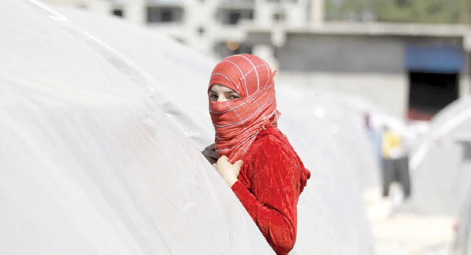 شابة سورية تنظر من خلف خيمتها في مخيم سوروس للاجئين السوريين في تركيا (إ.ب.أ)