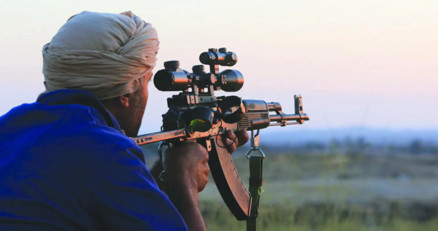 عنصر من مليشيات فجر ليبيا في جنوب طرابلس يصوب سلاحه نحو مقاتلين من اتجاه منطقة النواحي الأربع (أ.ف.ب)