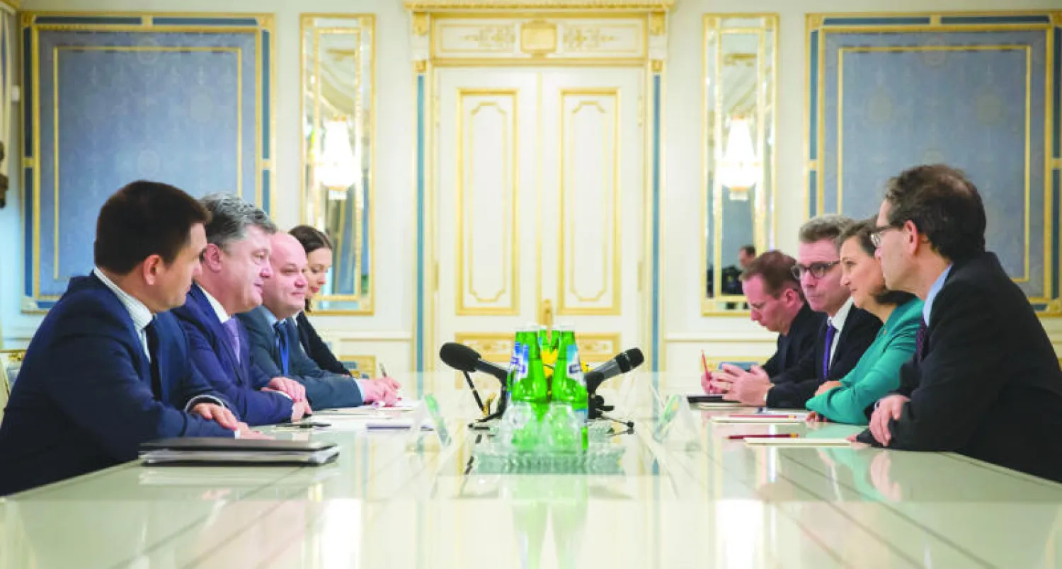 الرئيس الأوكراني بيترو بوروشينكو (الثاني يسارا) أثناء اجتماعه مع مساعدة وزير الخارجية الأميركي فيكتوريا نولاند (الثانية يمينا) في كييف أمس (أ.ف.ب)