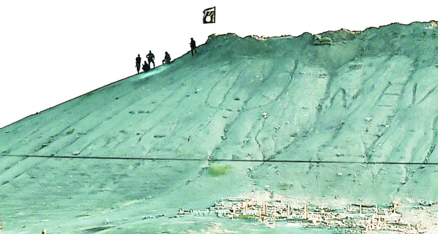 علم {داعش} وعناصر من التنظيم فوق أحد التلال المطلة على مدينة كوباني الكردية من الجانب التركي أمس (أ.ف.ب)