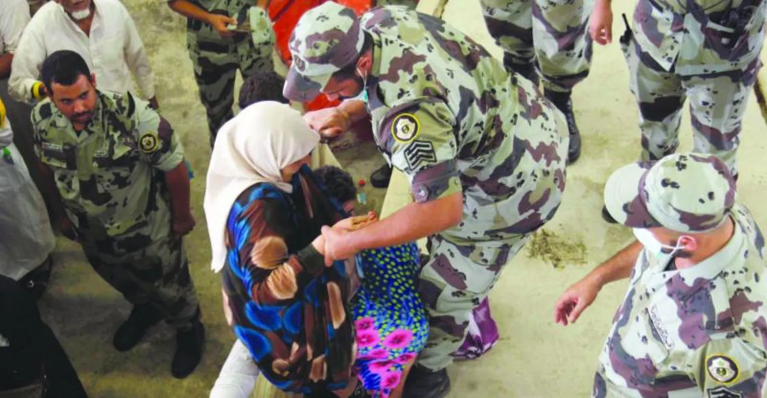 عنصر من قوات أمن الحج يقوم بمساعدة حاجة في أثناء رمي جمرة العقبة