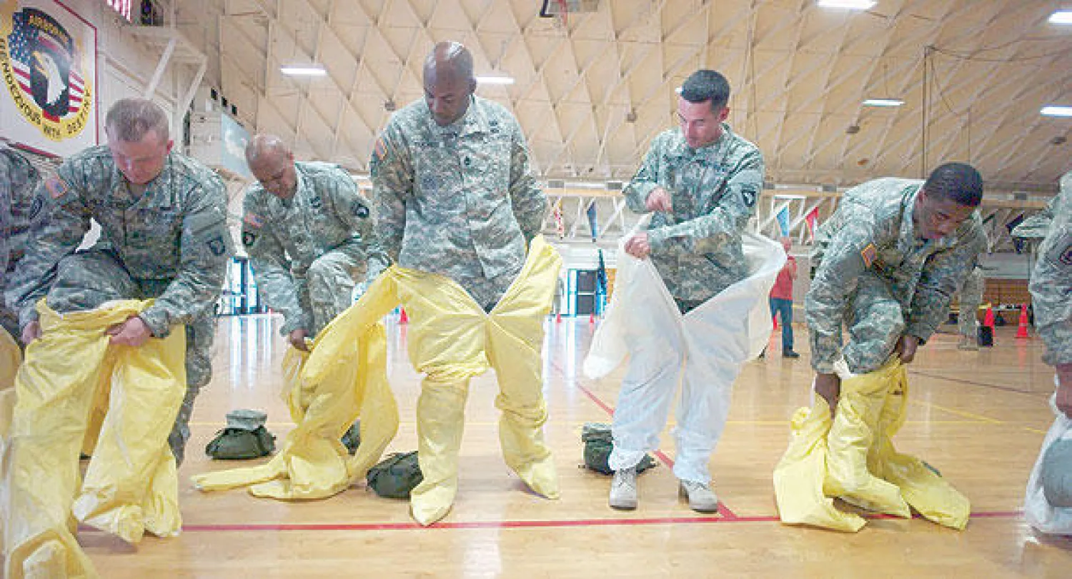 جنود أميركيون يتدربون على ارتداء الملابس الواقية في قاعدة فورت كامبل بولاية كنتاكي أول من أمس  قبل توجههم إلى غرب أفريقيا للمساعدة في مواجهة فيروس إيبولا (رويترز)