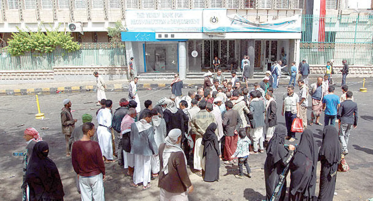 يمنيون يتجمعون أمس أمام المقر الرئيسي لبنك اليمن لإعادة الإعمار في صنعاء وذلك بعد تعرضه لعمليات تفجير أول من أمس (أ. ف. ب)