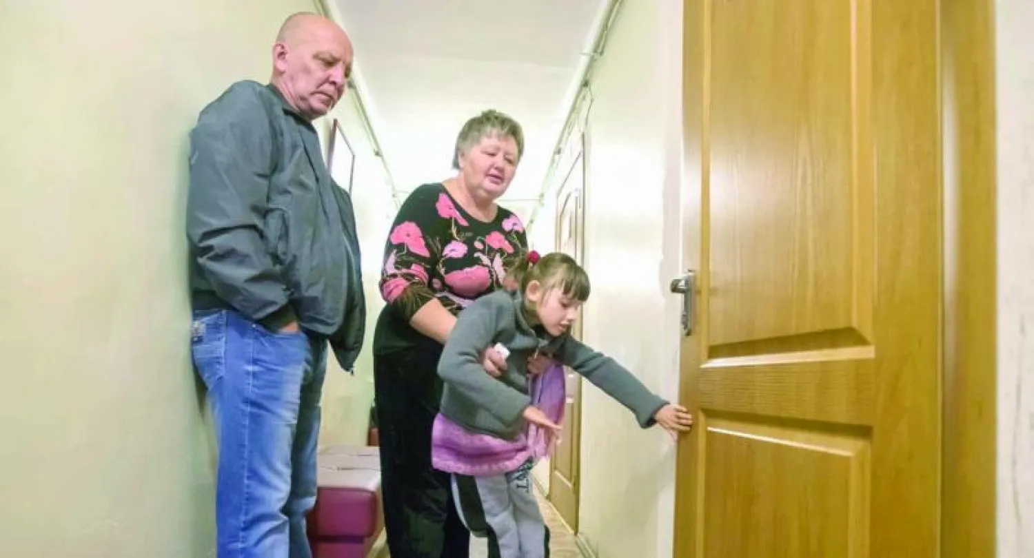 تامارا تحمل حفيدتها ماريا التي تعاني من شلل دماغي  في عيادة بمدينة دونيتسك الواقعة شرق أوكرانيا أمس (رويترز)