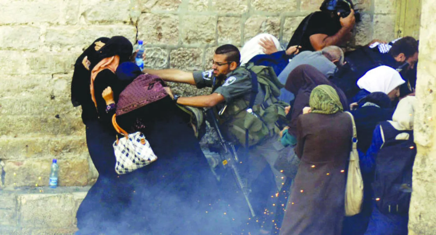 رجال شرطة إسرائيليون يدفعون فلسطينيات مساء أول من أمس أمام مسجد الأقصى (أ.ب)
