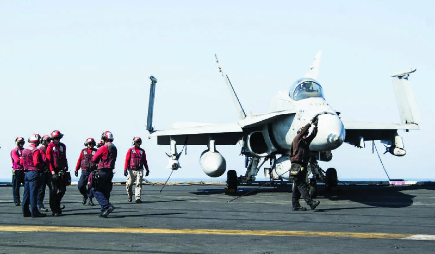 جنود فوق حاملة الطائرات الأميركية «يو إس إس جورج دبليو بوش» يجهزون طائرة مقاتلة قبل أن تنطلق لضرب أهداف «داعش» (أ.ف.ب)