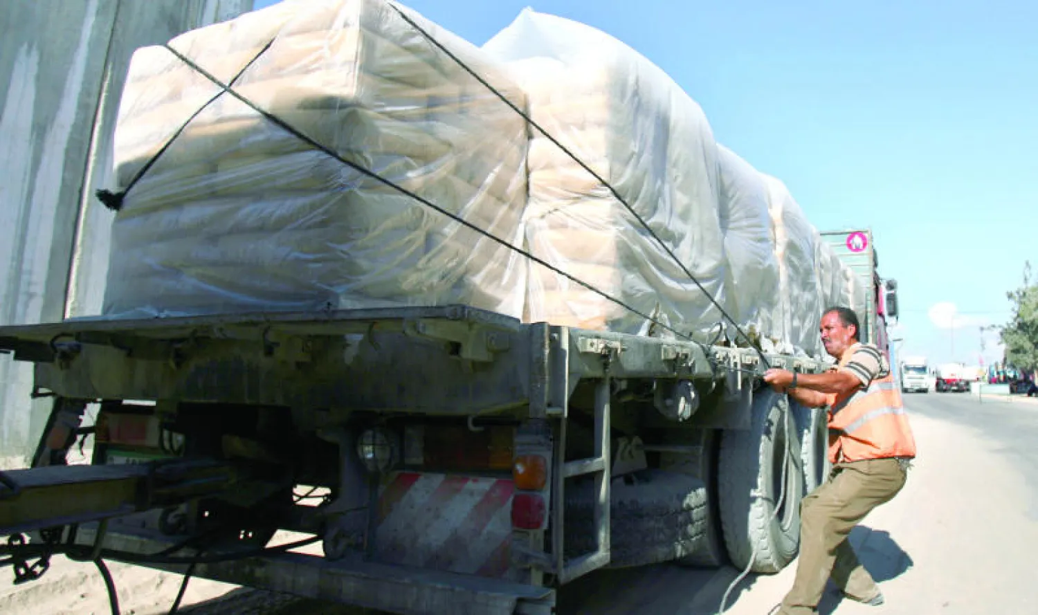 عامل مصري يعمل على تأمين أكياس من الإسمنت في شاحنة عند معبر كرم أبو سالم باتجاه رفح آتية من إسرائيل لإعمار غزة (أ.ب)