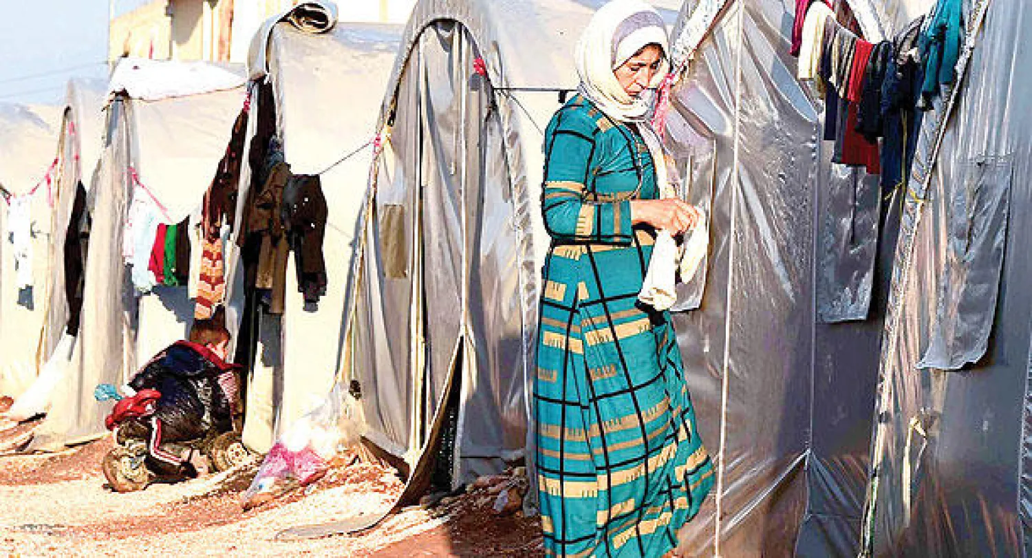 لاجئة كردية تقف خارج خيامهن في ملجأ سوروك التركية أمس (أ.ف.ب)