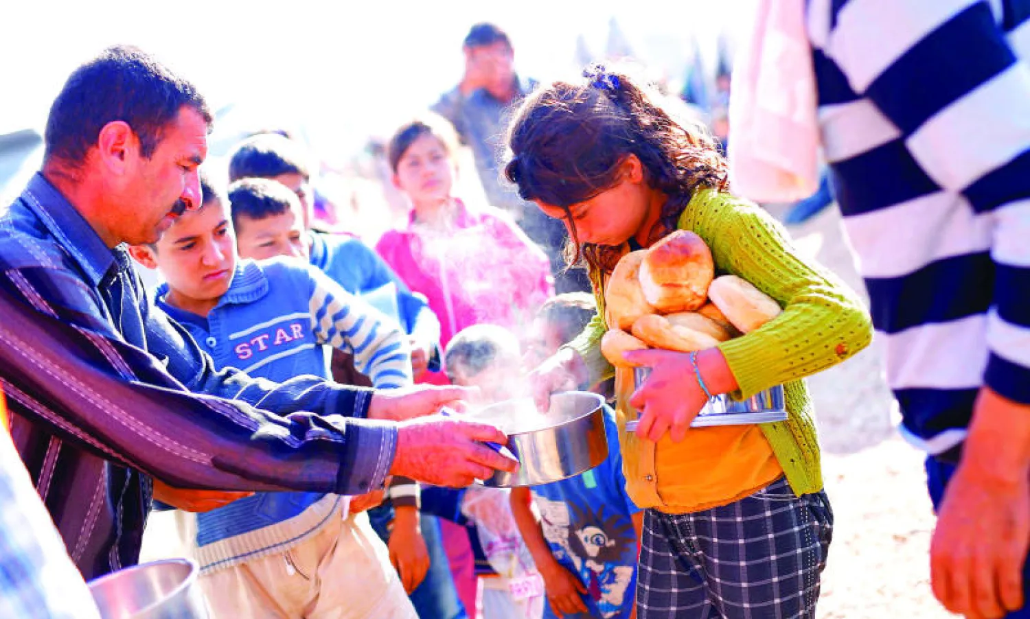 أطفال لاجئون من مدينة كوباني السورية يتلقون مساعدات غذائية في مخيم بمدينة سروج التركية على الحدود مع سوريا أمس (رويترز)