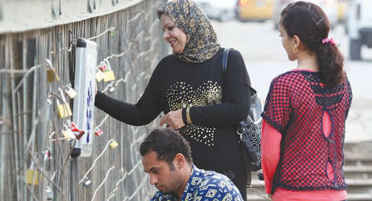 عراقيون يعلقون أقفالا على «جسر الحب» في البصرة (أ.ف.ب)