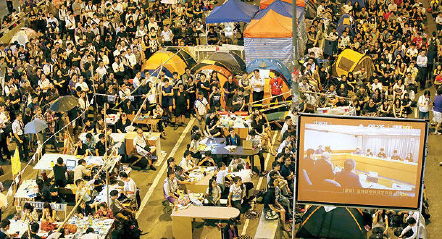 متظاهرون يشاهدون بثا مباشرا لجلسة المفاوضات بين ممثلين عنهم ومسؤولي الحكومة، من حي أدميراتلي في هونغ كونغ أمس (إ.ب.أ)