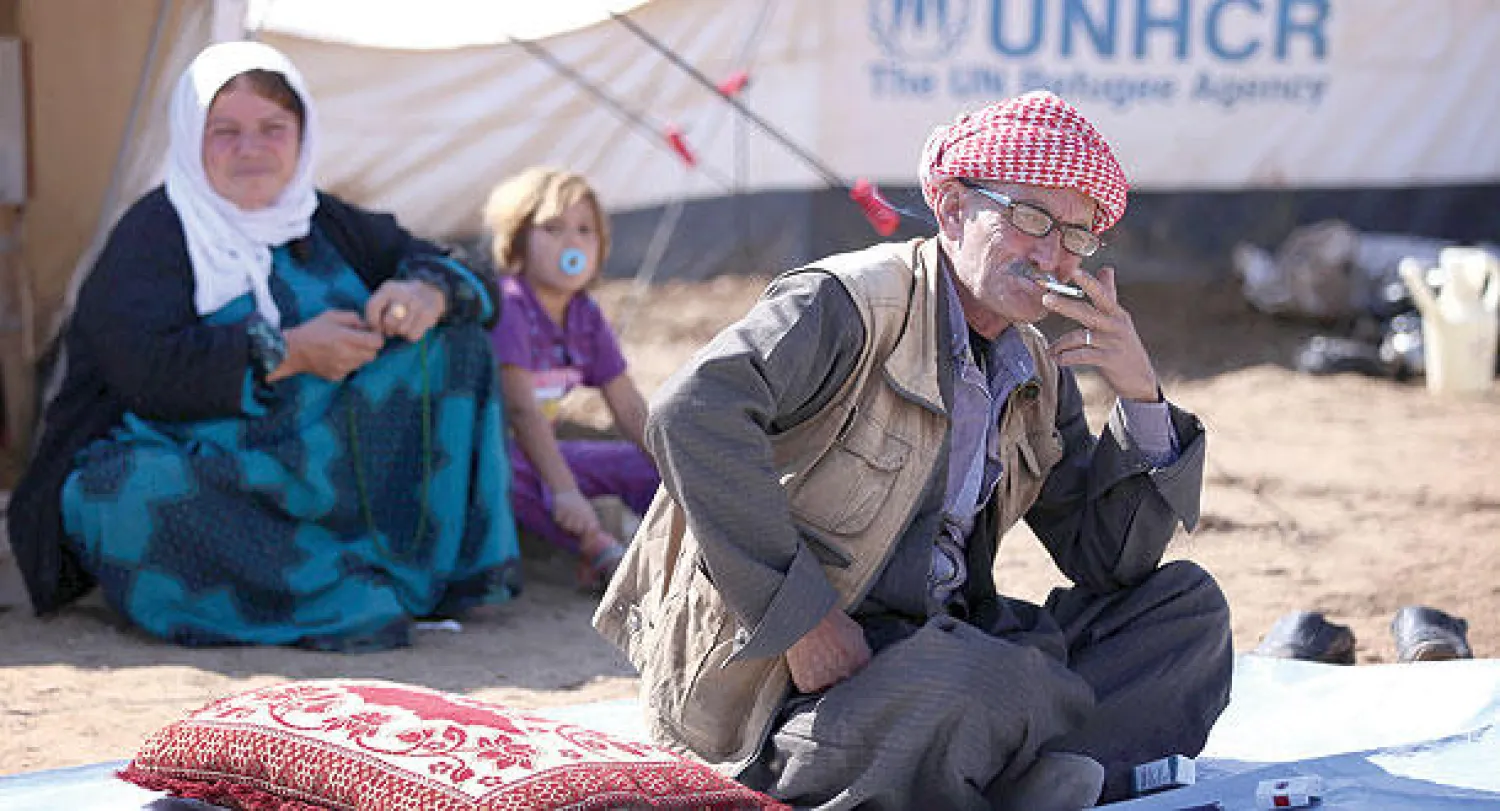 أفراد أسرة إيزيدية نازحة من سنجار يجلسون أمام خيمتهم في مخيم بإقليم كردستان العراق (أ.ف.ب)