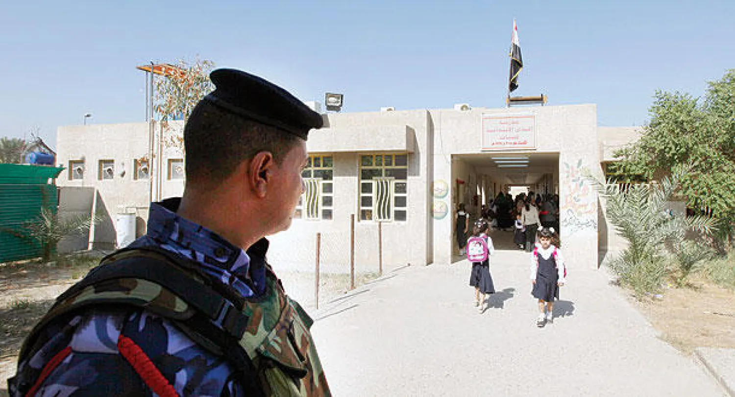 شرطي يحرس مدرسة في بغداد مع بدء العام الدراسي الجديد أمس (رويترز)