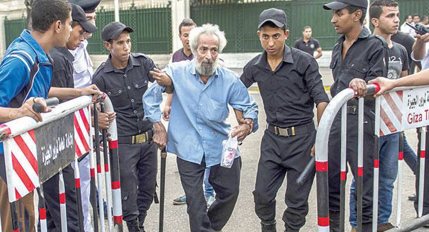 عناصر من الشرطة المصرية يساعدون مسنا نجا من الانفجار في القاهرة أمس (أ.ف.ب)