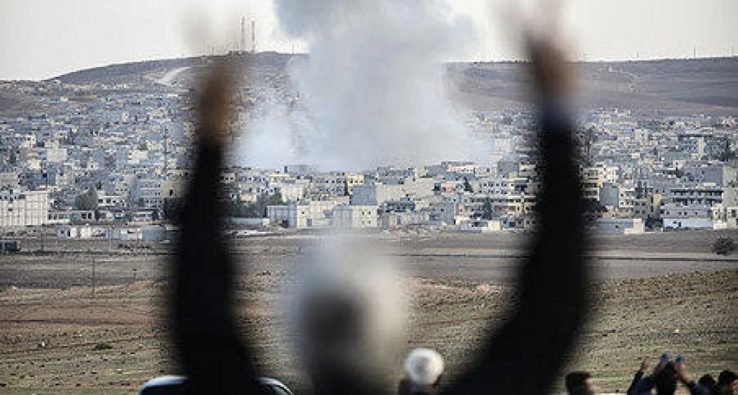 سوريون يعاينون التفجيرات في كوباني من قرية مرشد بينار التركية الحدودية مع سوريا امس (أ.ف.ب)