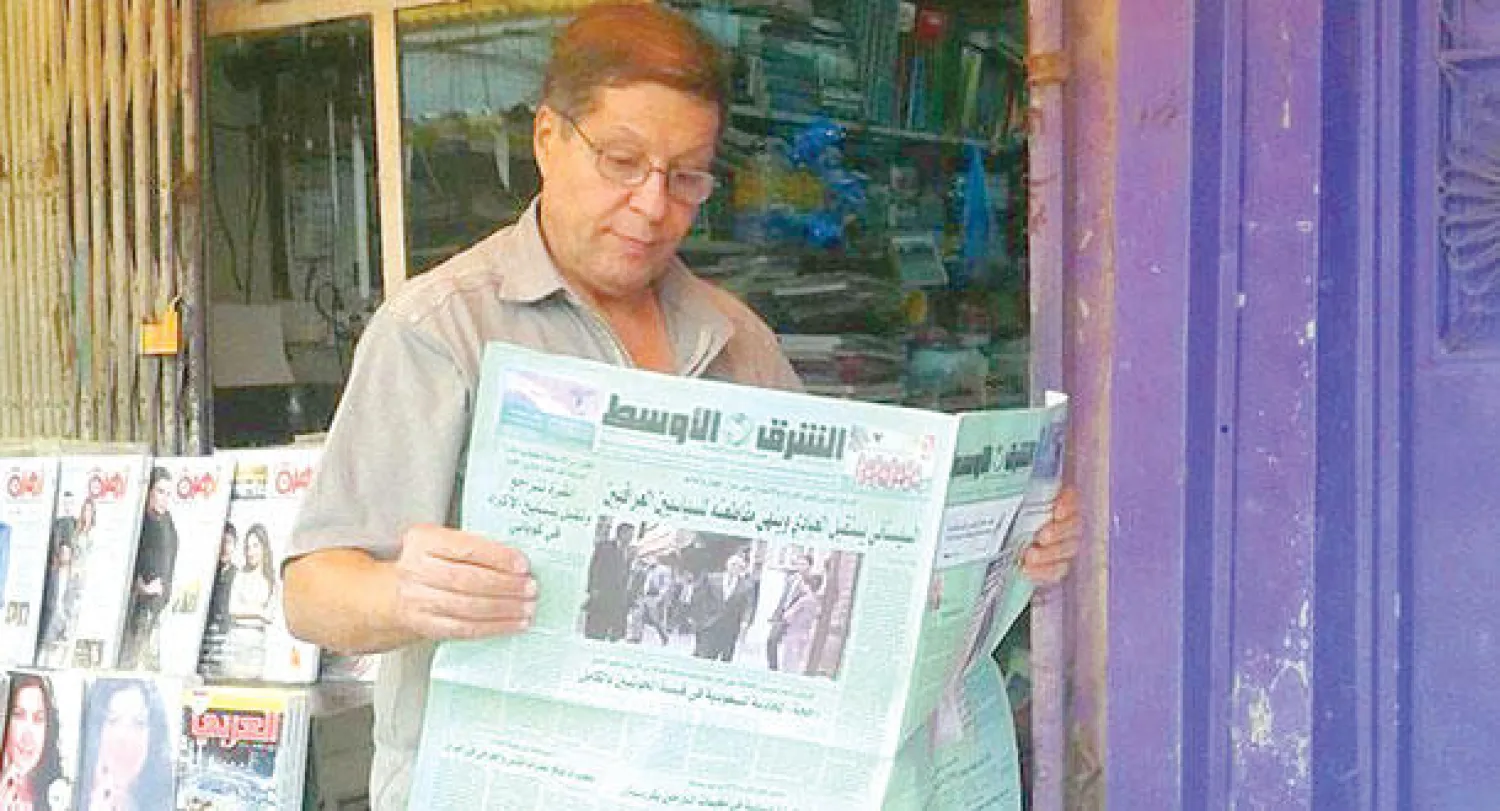 عراقي يتصفح «الشرق الأوسط» عند كشك لبيع الصحف في بغداد أمس