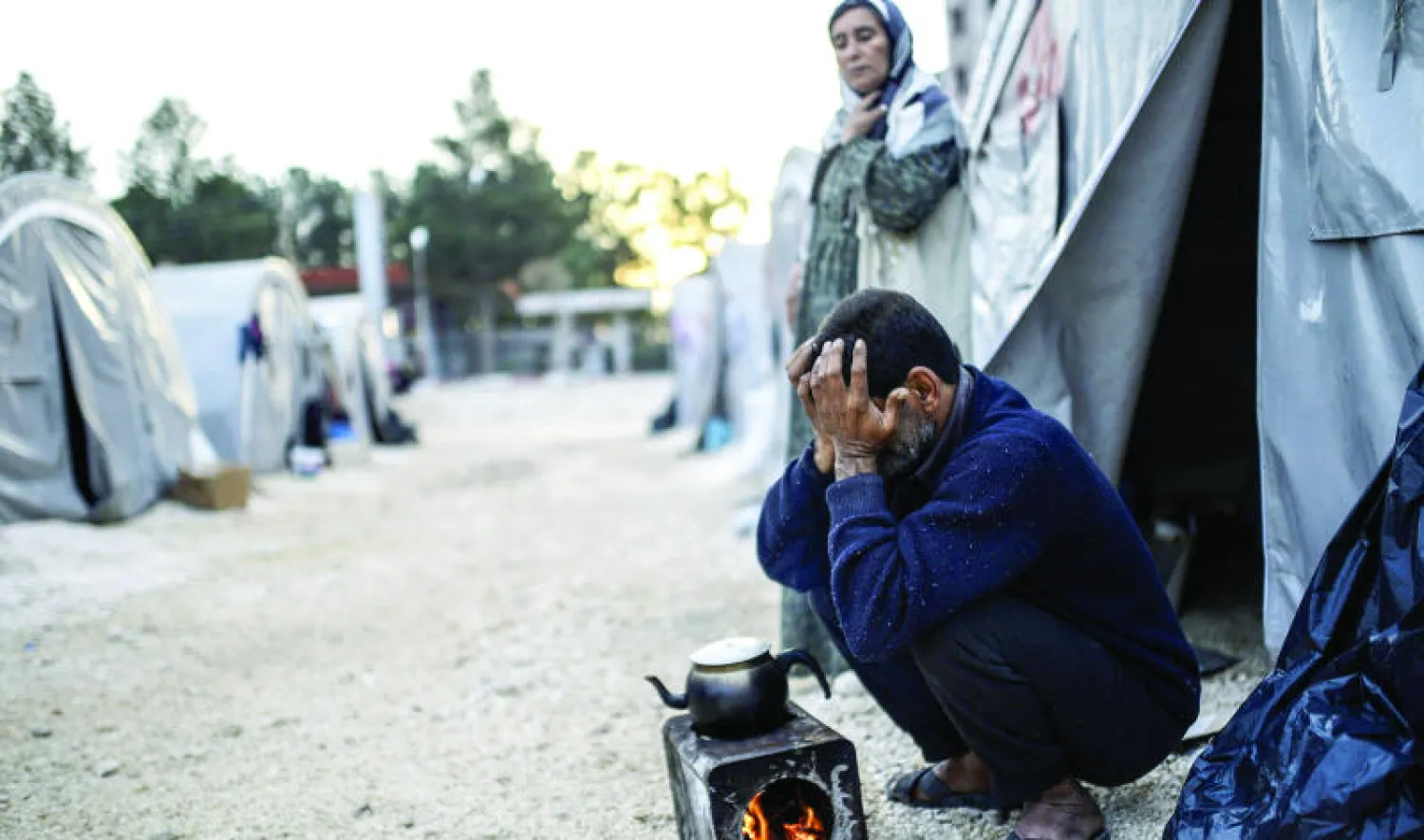 أحد اللاجئين الأكراد أمام موقد الشاي في مخيم «روجوفا» للاجئين في سوروك الحدودية التركية أمس (أ.ف.ب)