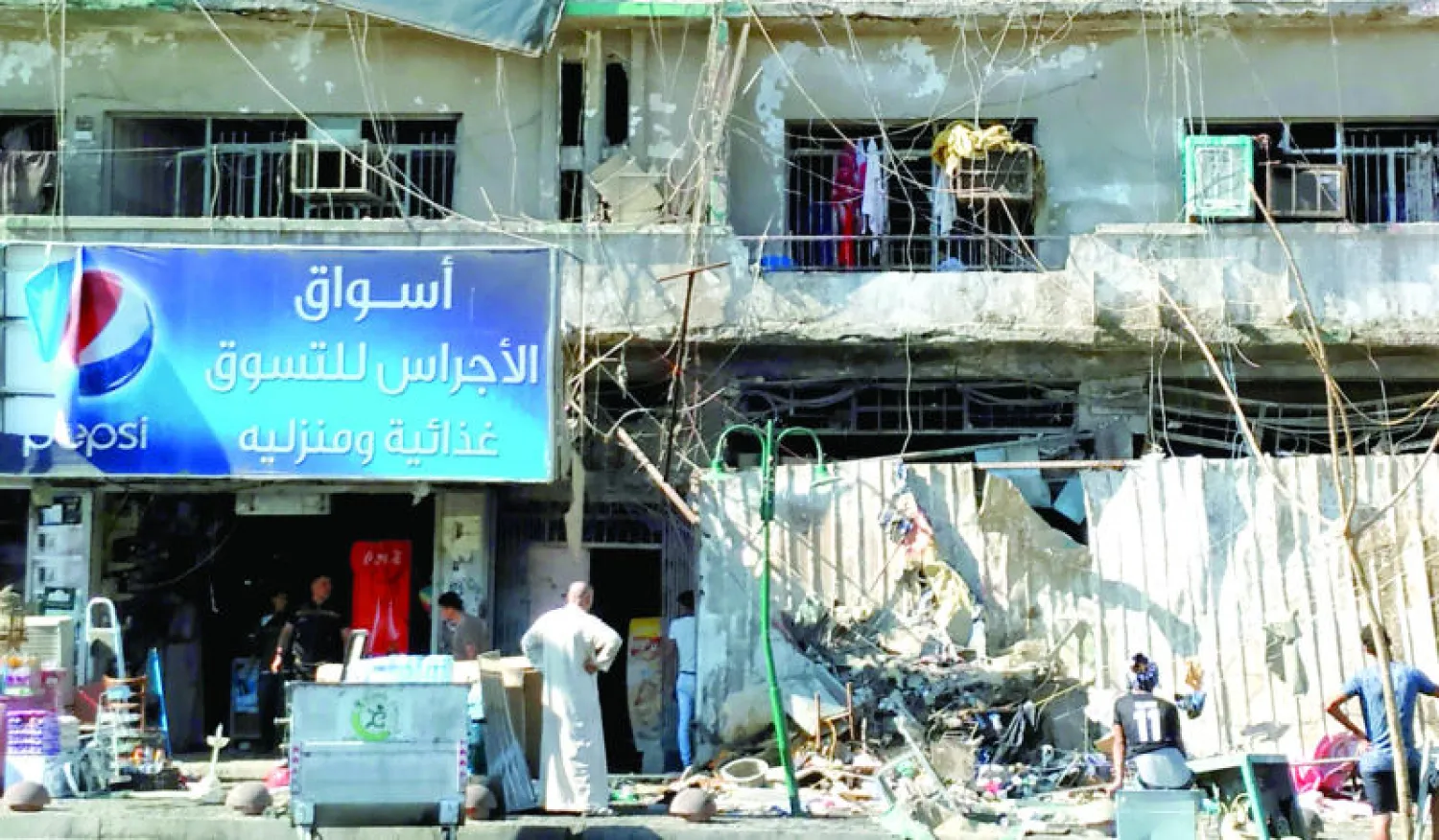 عراقيون يتفحصون موقع انفجار سيارة مفخخة بحي الكرادة وسط بغداد أمس أدى إلى مقتل وجرح ما يقرب من 40 مواطنا (إ.ب.أ)