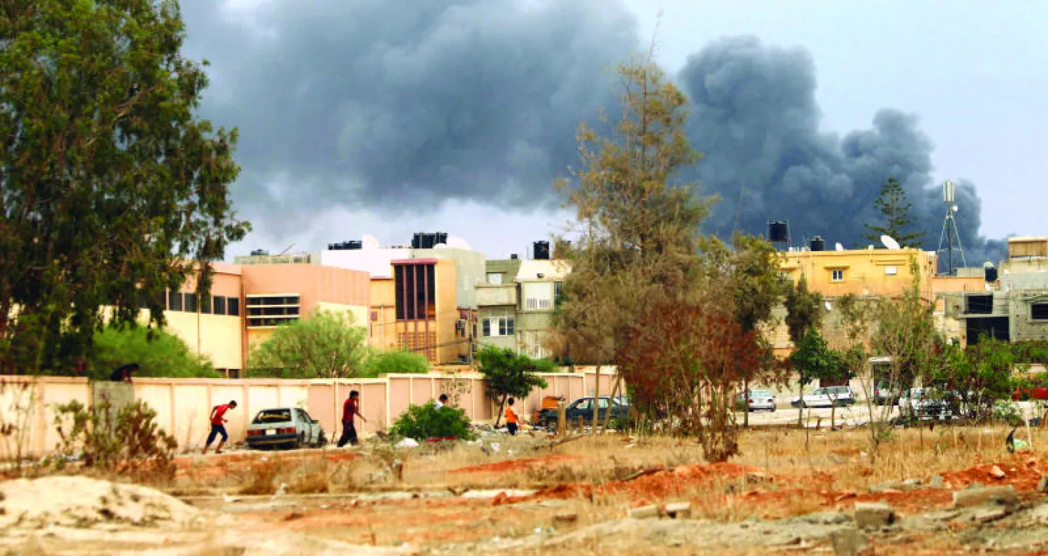 الدخان يتصاعد أول من أمس من أبنية غارت عليها طائرات ليبية تابعة للجنرال خليفة حفتر وكانت تستخدم كمخازن ذخيرة من قبل جماعة {أنصار الشريعة} الإسلامية في بنغازي (أ.ف.ب)