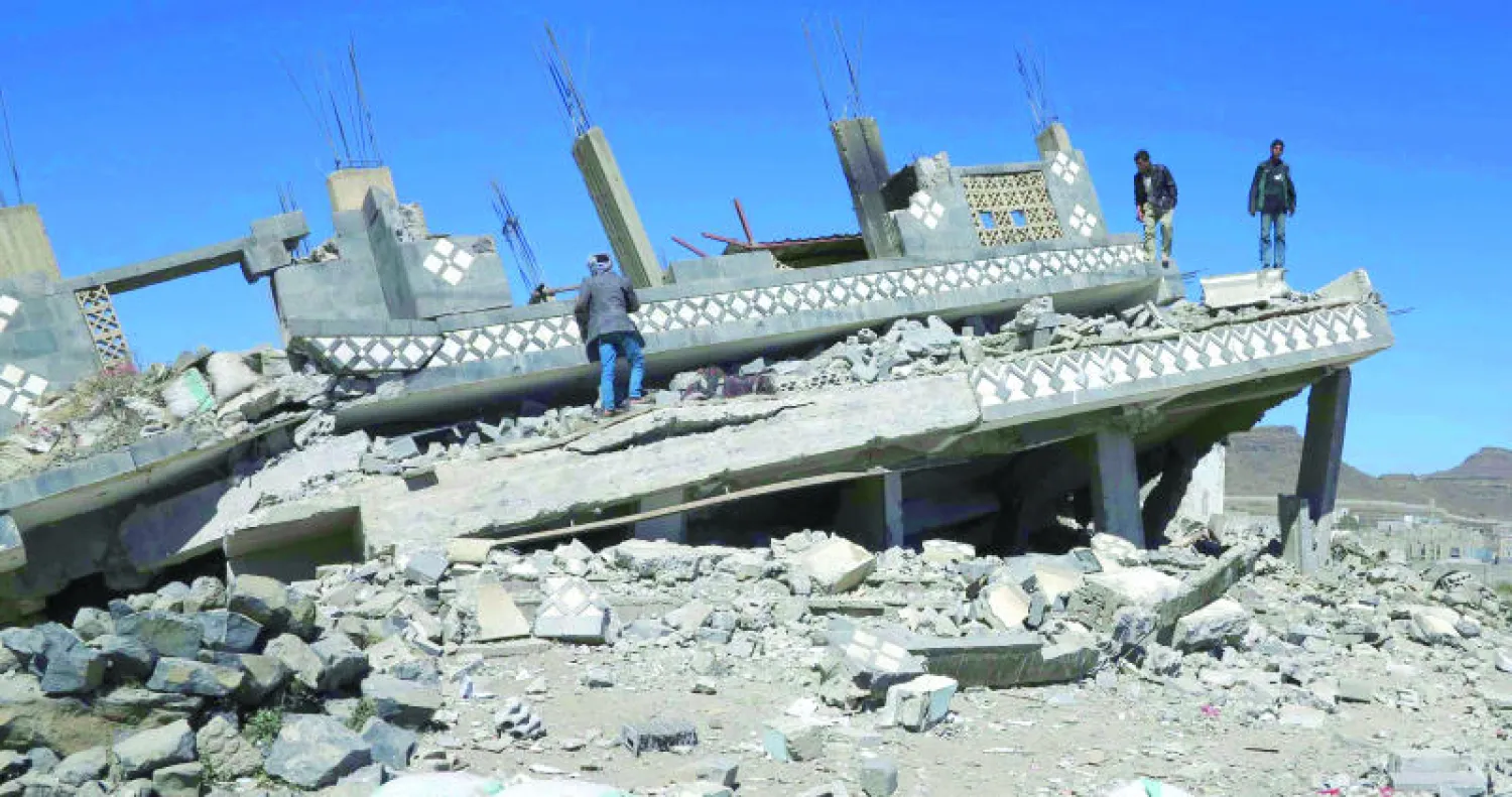 يمنيون يقفون على أطلال بيت هدمه الحوثيون في محافظة إب (رويترز)