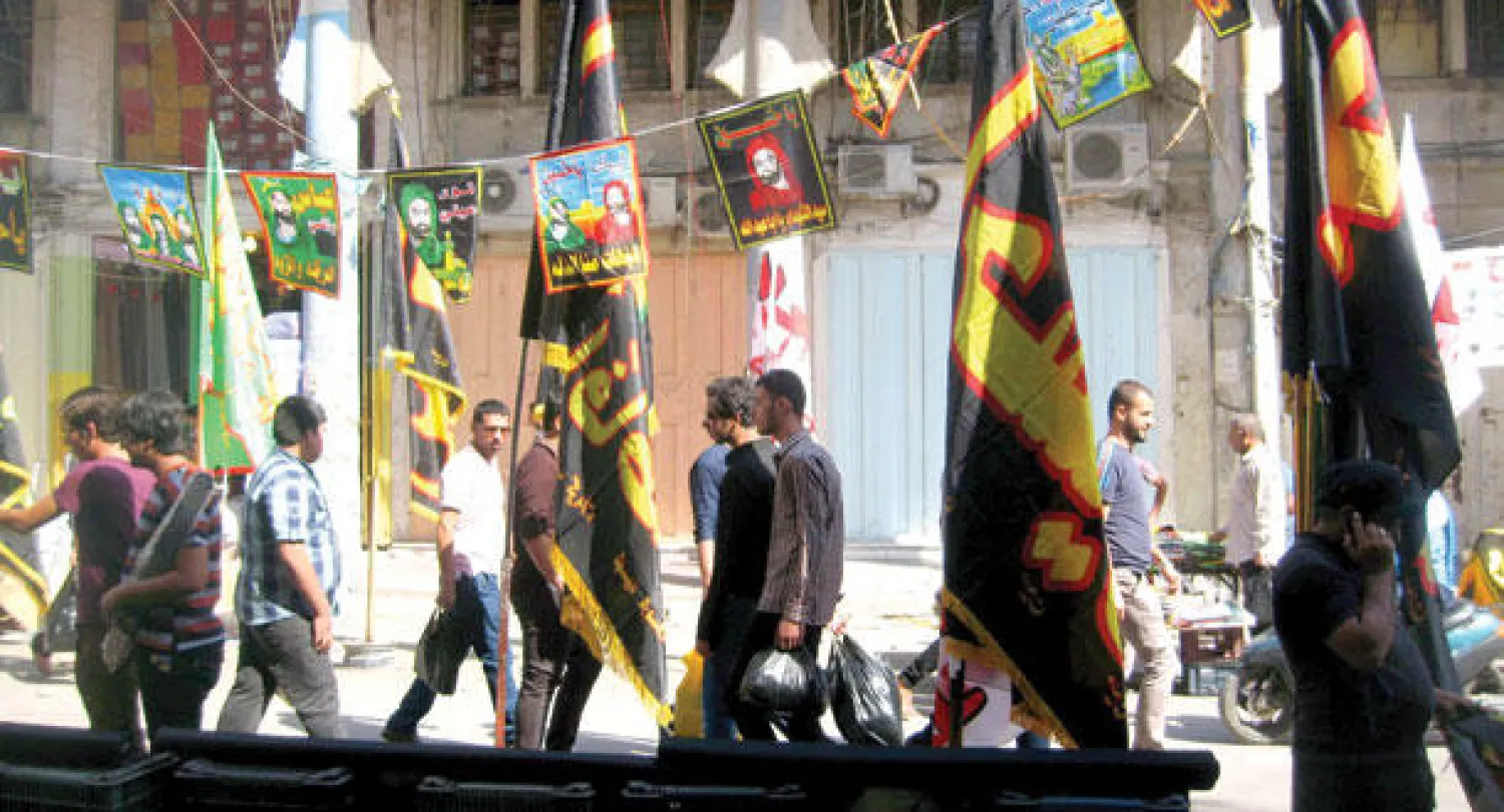 عراقيون يقطعون شارع المتنبي وسط بغداد بينما تتهادى رايات وشعارات أمس بمناسبة بدء شهر محرم (إ.ب.أ)