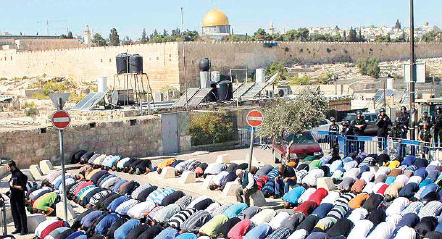 فلسطينيون يؤدون صلاة الجمعة في منطقة رأس العمود بعد وضع القوات الإسرائيلية قيودا على دخول المصلين إلى المسجد الأقصى أمس (رويترز)