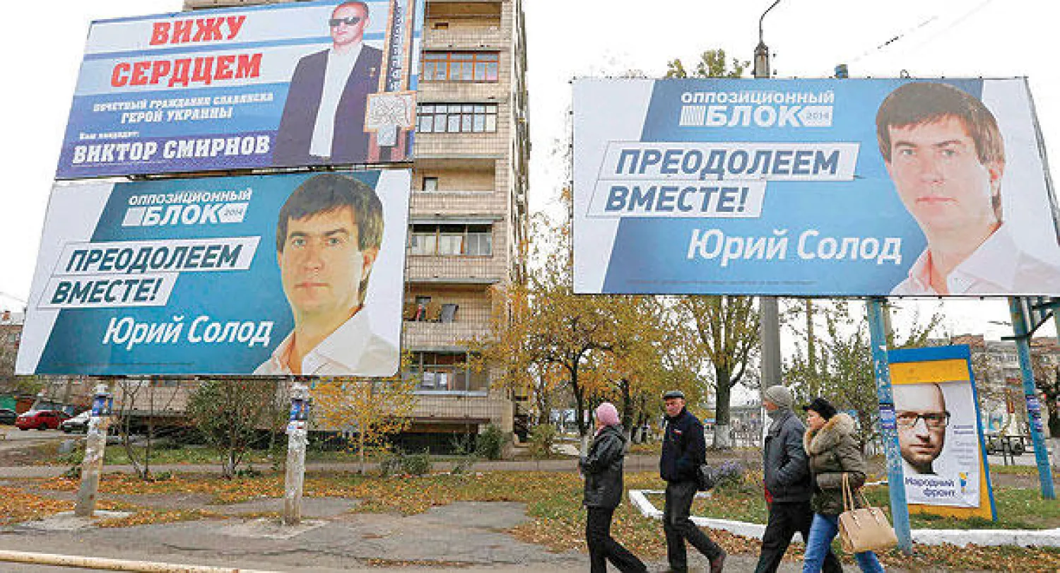 أوكرانيون يمرون أمام إعلانات انتخابية في مدينة سلافيانسك بشرق البلاد أمس (رويترز)