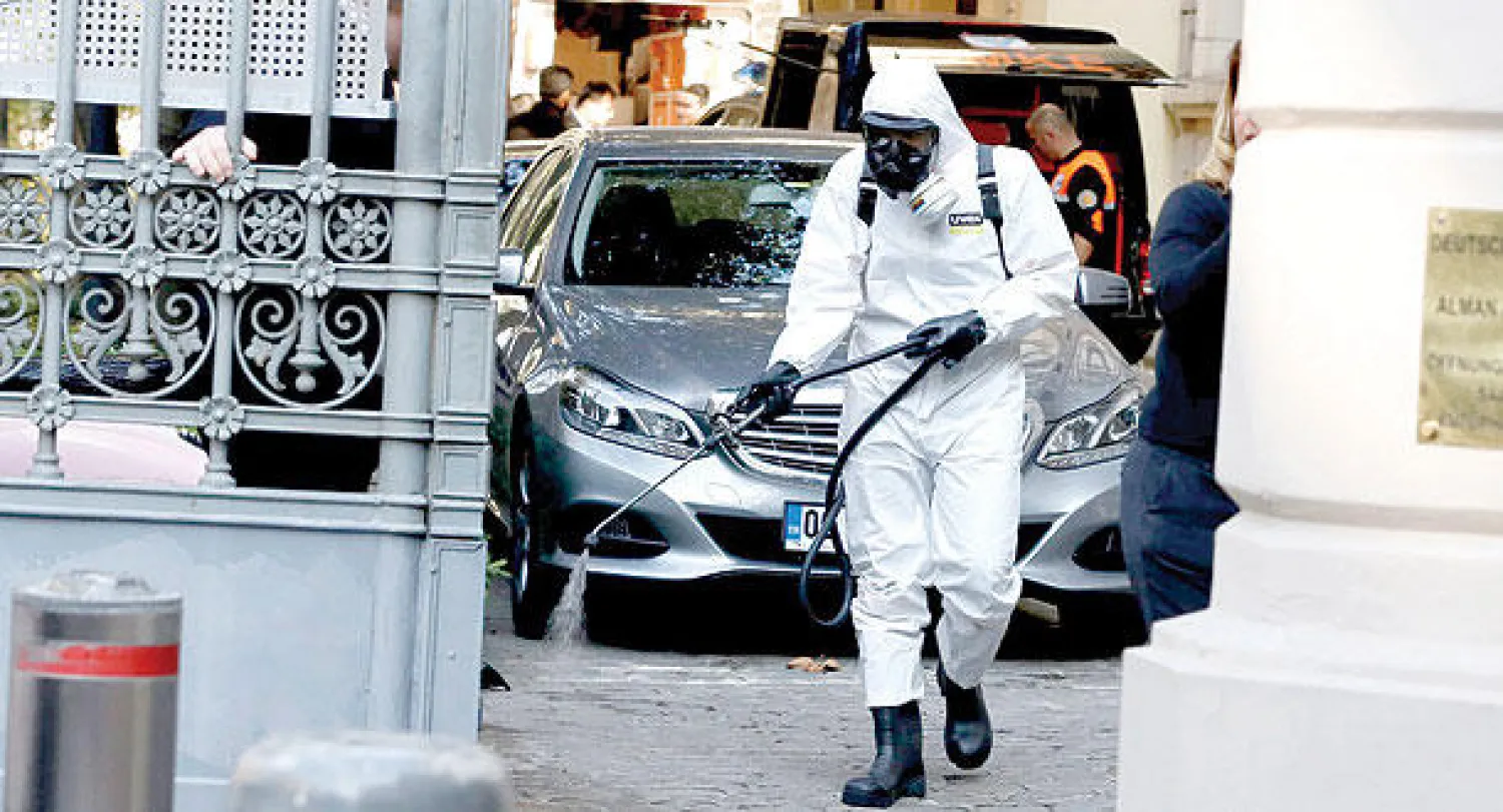 أحد عمال إدارة الكوارث والطوارئ التركية يقوم برش مبيدات مضادة في مدخل القنصلية الألمانية في إسطنبول أمس (إ.ب.أ)