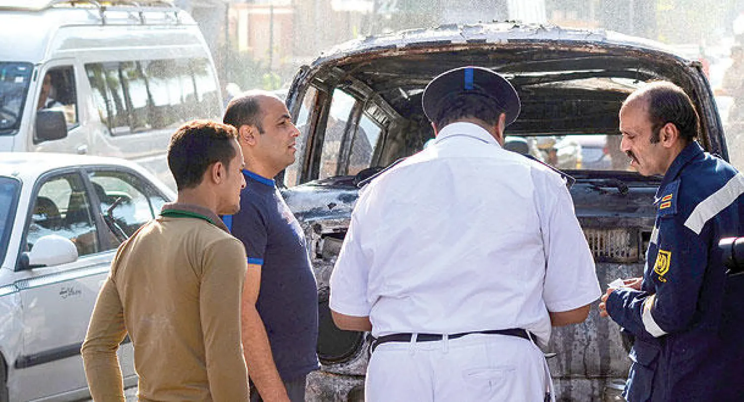 رجل أمن مصري يعاين سيارة أحرقت أثناء المواجهات بين قوات الأمن وعناصر مؤيدة لجماعة الأخوان المسلمين في الجيزة أمس (غيتي)