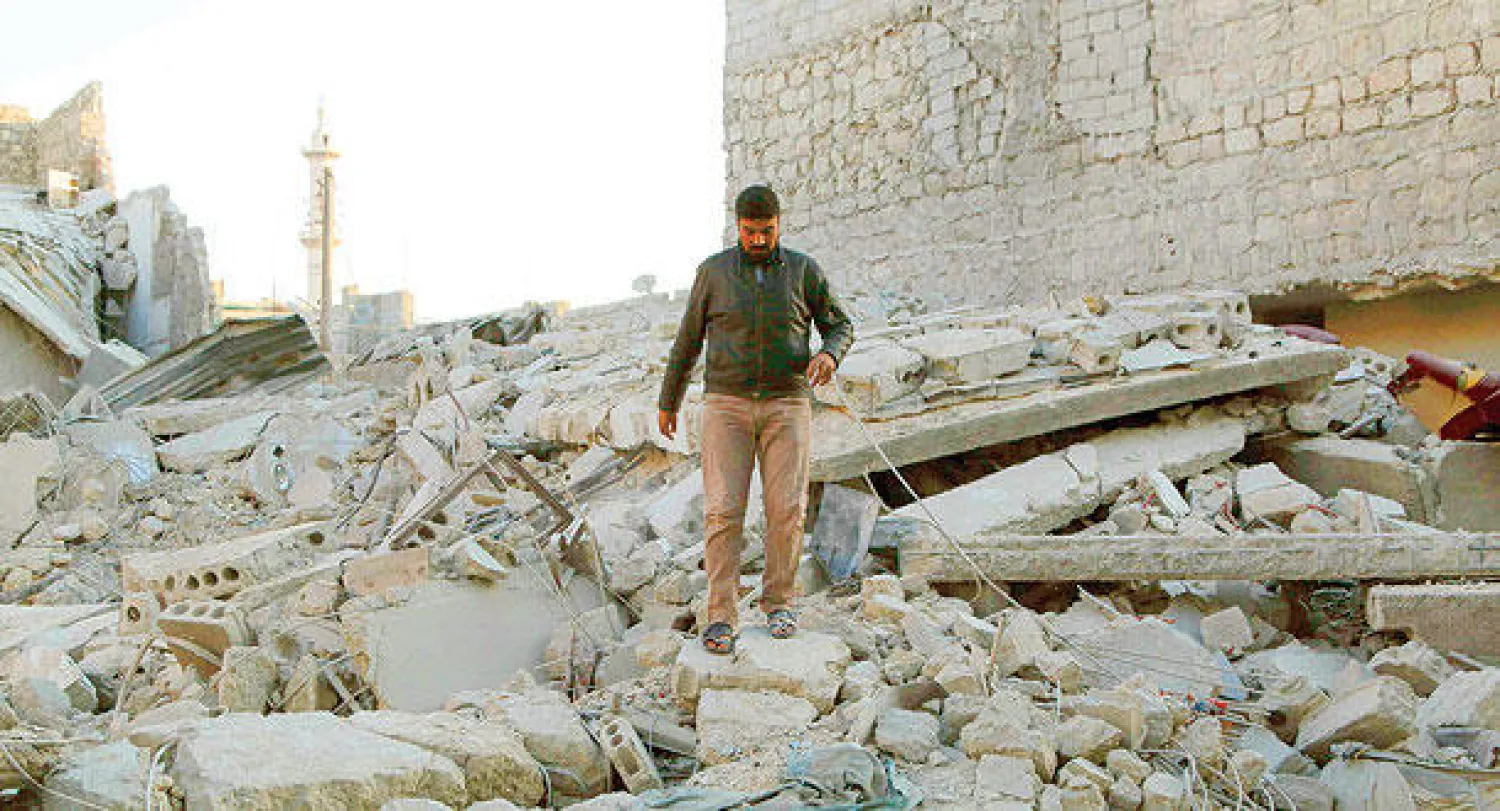 سوري يسير على أنقاض مبنى دُمر جراء غارة نظامية ببرميل متفجر  استهدف حي الحيدرية في حلب أمس (رويترز)