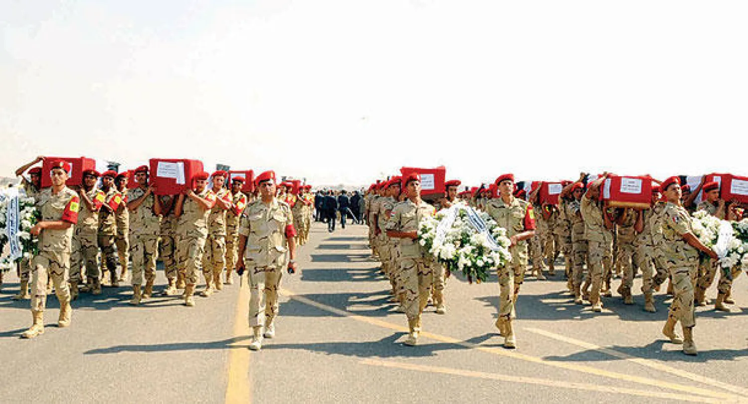 جنود مصريون يحملون في جنازة عسكرية نعوش زملائهم الذين قتلوا في هجوم انتحاري بشمال سيناء أول من أمس (رويترز)