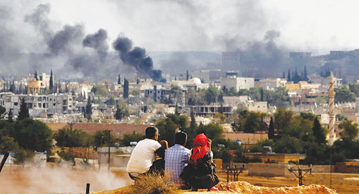 أعمدة الدخان تتصاعد من كوباني وبعض من أهاليها يراقبون الوضع بقلق عبر الحدود التركية أمس (رويترز)