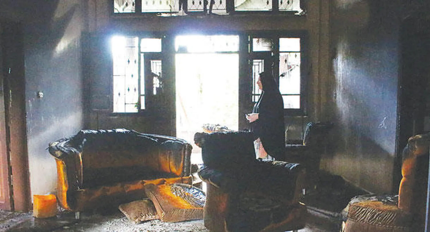 لبنانية تتفقد منزلها الذي احترق جراء اشتباكات بين الجيش ومسلحين في بلدة بحنين شمال لبنان أمس (رويترز)