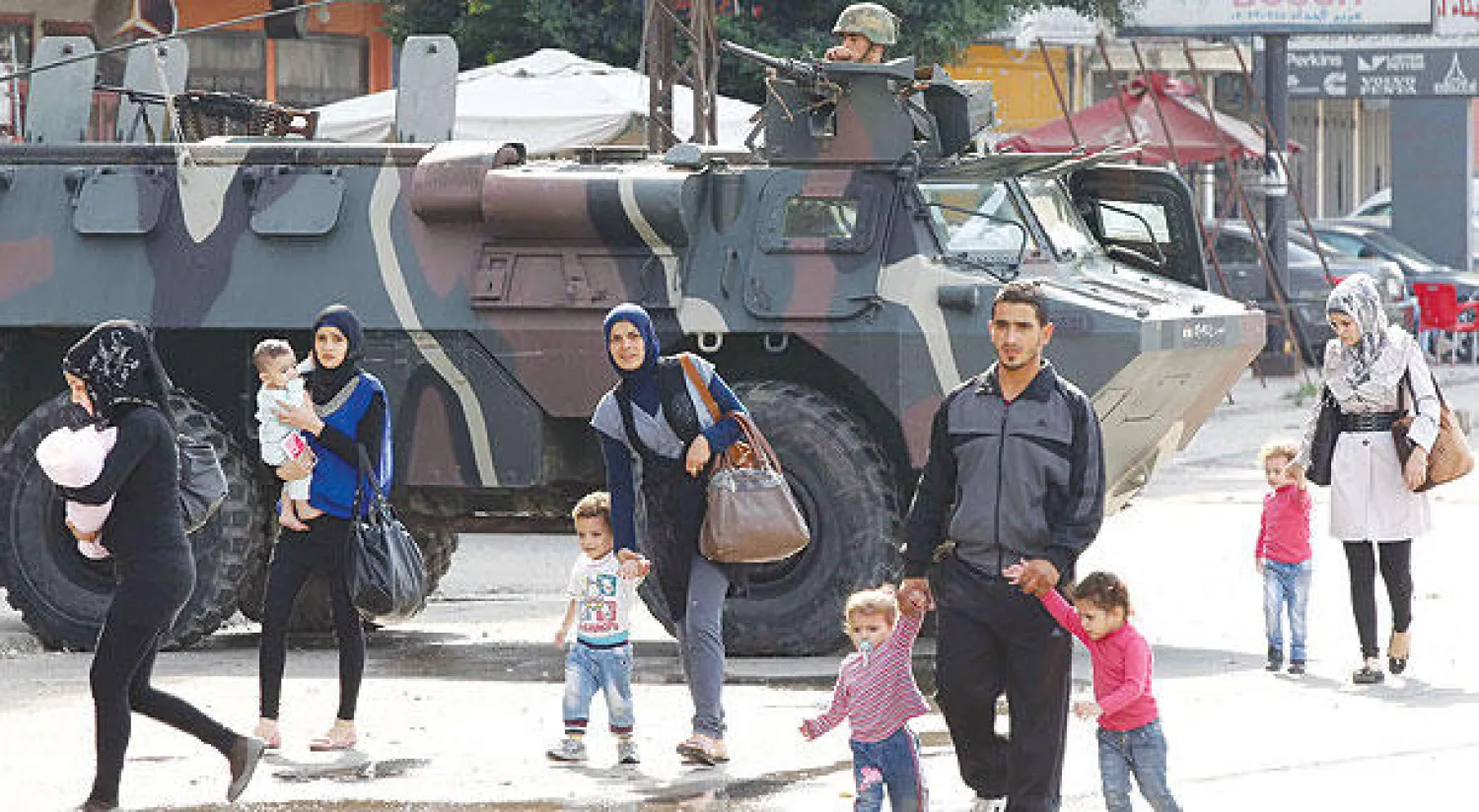 لبنانيون يمرون قرب عربة مدرعة تابعة للجيش اللبناني غداة اشتباكات بين الجيش ومسلحين في طرابلس أمس (رويترز)