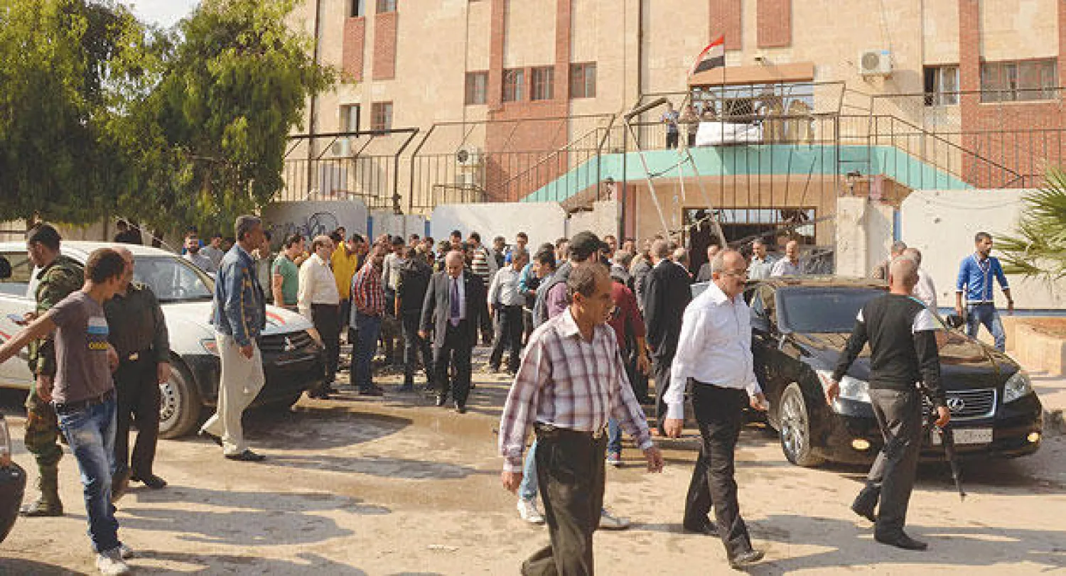 عناصر من الأمن السوري ومدنيون يتفقدون مدرسة بعد إصابتها بقذيفة هاون في منطقة الحمدانية بحلب أمس (رويترز)