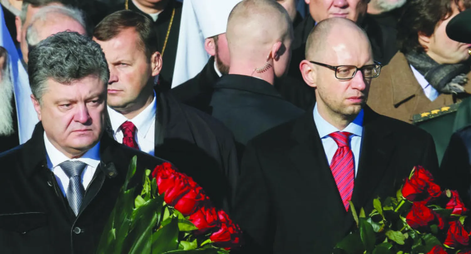 الرئيس بوروشينكو (يسار) ورئيس الوزراء ياتسينيوك يحملان وردا قبل وضعه أمام قبر الجندي المجهول في كييف أمس في إطار إحياء الذكرى السبعين لتحرير أوكرانيا من النازية خلال الحرب العالمية الثانية (رويترز)