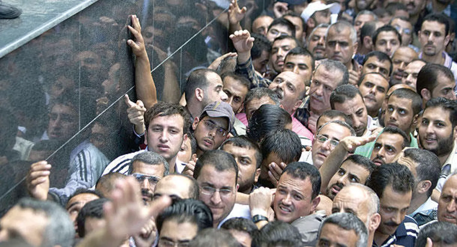 آلاف الموظفين في حكومة حماس السابقة اصطفوا أمس أمام مدخل مكاتب البريد في غزة لتلقي دفعة من رواتبهم (أ.ف.ب)