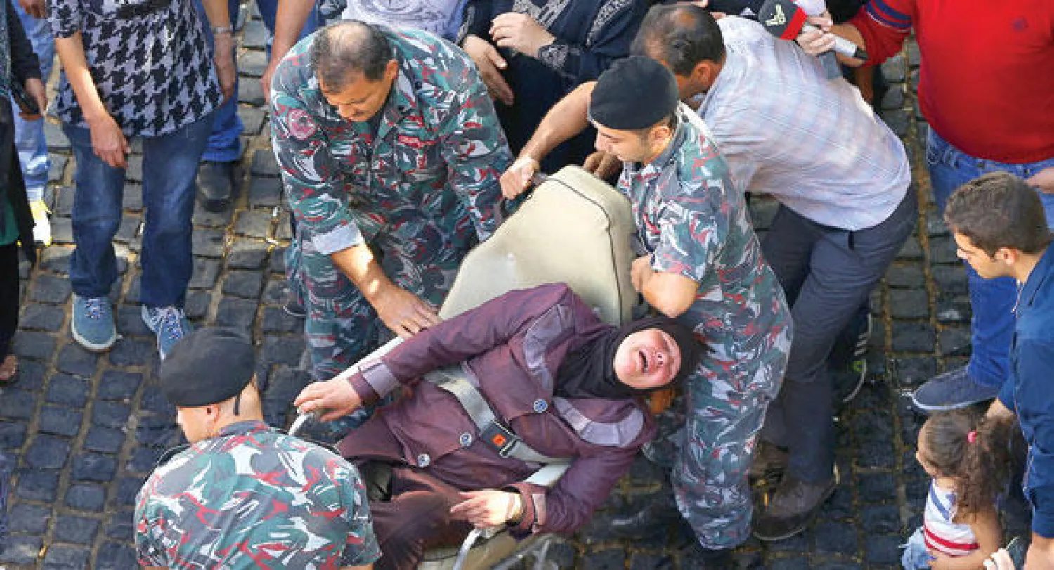 والدة أحد الجنود المختطفين من قبل {داعش} و{النصرة} أثناء إنقاذها بعد محاولة إشعال النيران في جسدها في بيروت أمس (أ.ب)