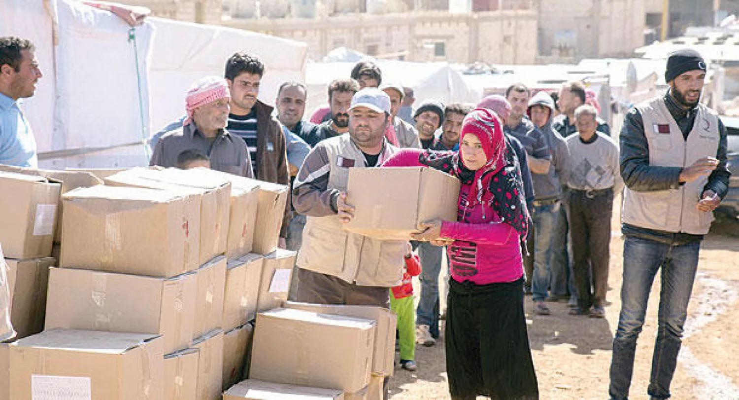 منظمة إغاثية غير حكومية توزع صناديق على اللاجئين السوريين  تحتوي على مواد إغاثية في مخيم {المصري} للاجئين (أ.ف.ب)