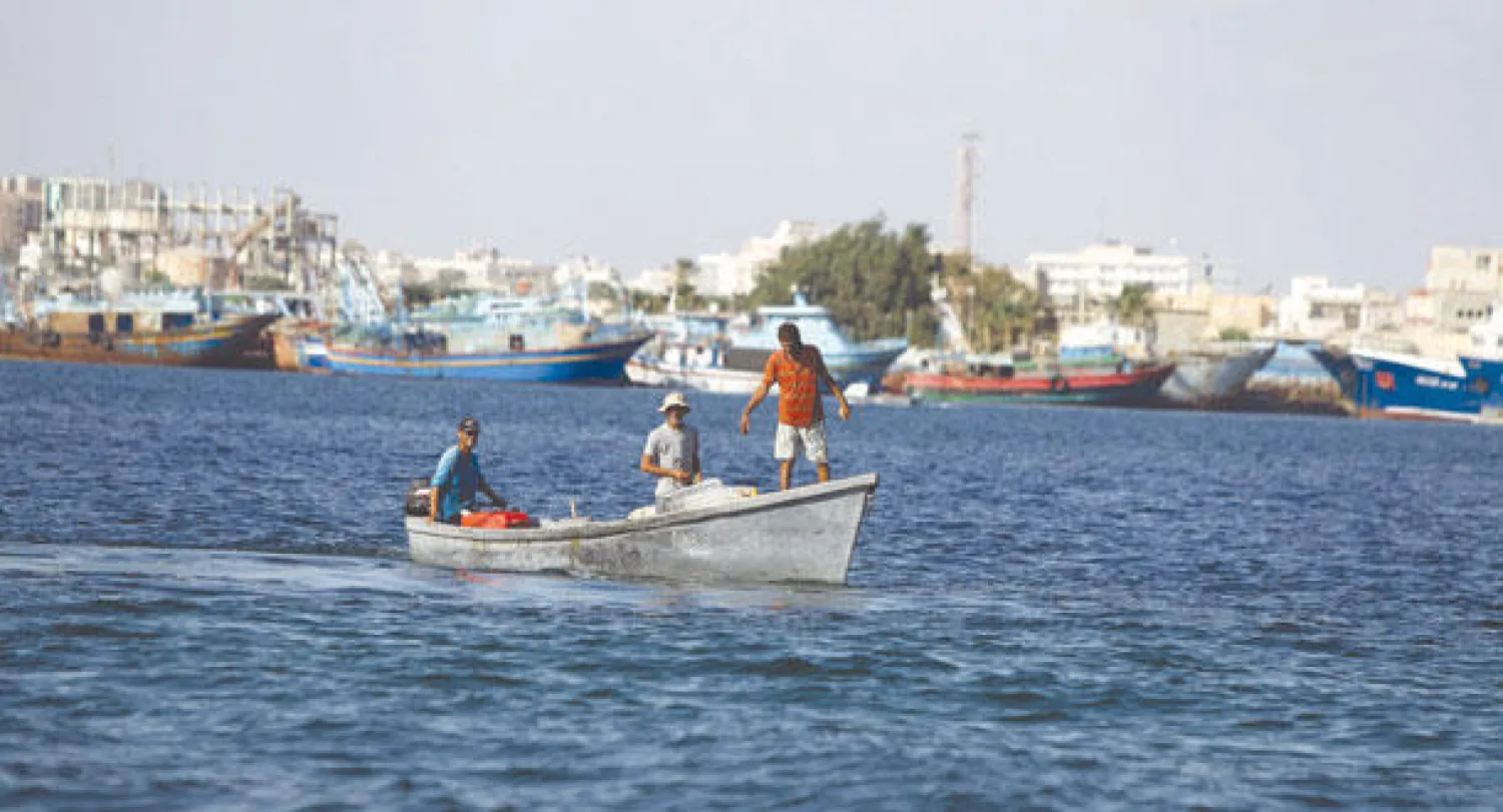 ليبيون في قارب بالقرب من ميناء بنغازي الذي شهد امس اشتباكات مسلحة  بين المسلحين الاسلاميين وقوات الجيش الليبي « ا ف ب»