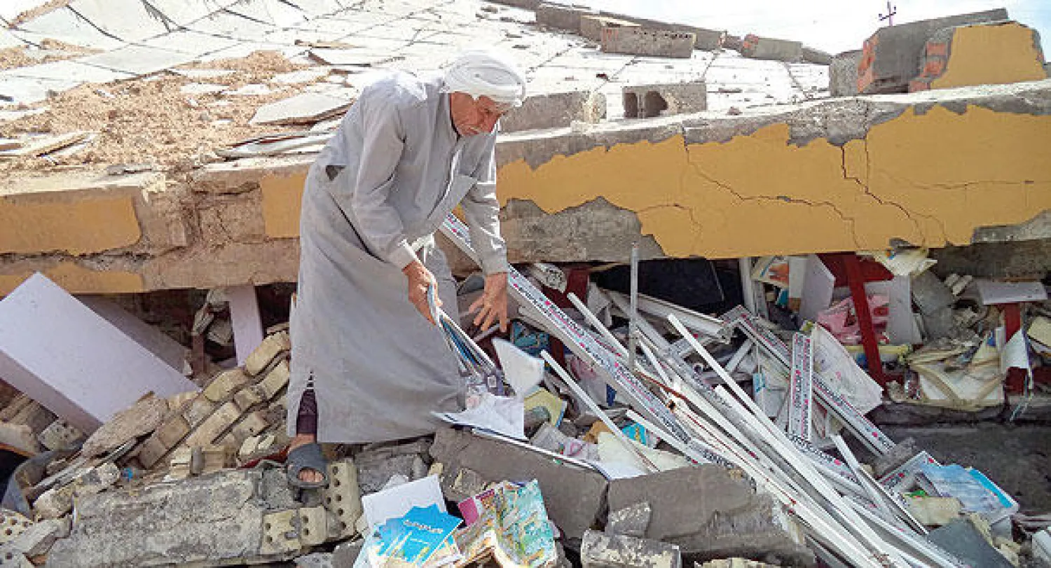 عراقي يفتش وسط أنقاض منزله الذي دمر في معارك بين القوات الأمنية ومسلحي «داعش»  في قرية قرب تكريت أمس (إ.ب.أ)