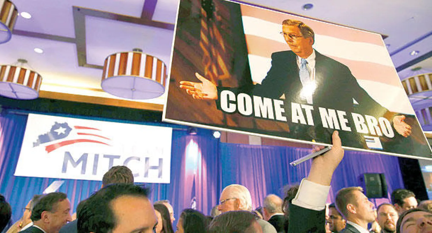 مناصر لميتش ماكونيل، الذي بات زعيما للأغلبية الجمهورية في مجلس الشيوخ، يحمل صورته خلال تجمع في لويسفيل بولاية كنتاكي مساء أول من أمس (رويترز)