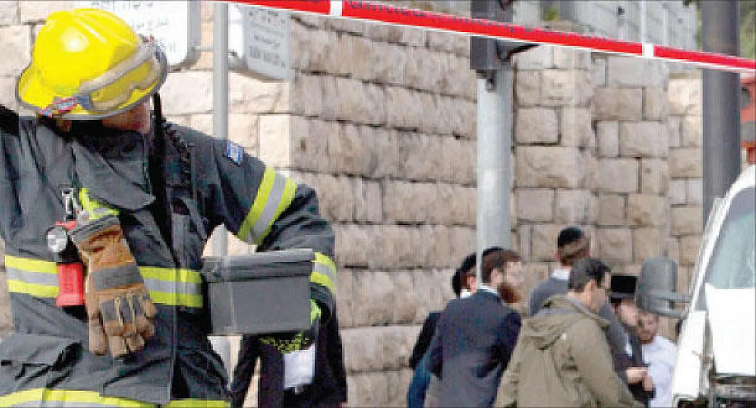 رجل إطفاء إسرائيلي يتفحص المكان الذي نفذت فيه عملية الدهس وسط مدينة القدس أمس (أ.ب)