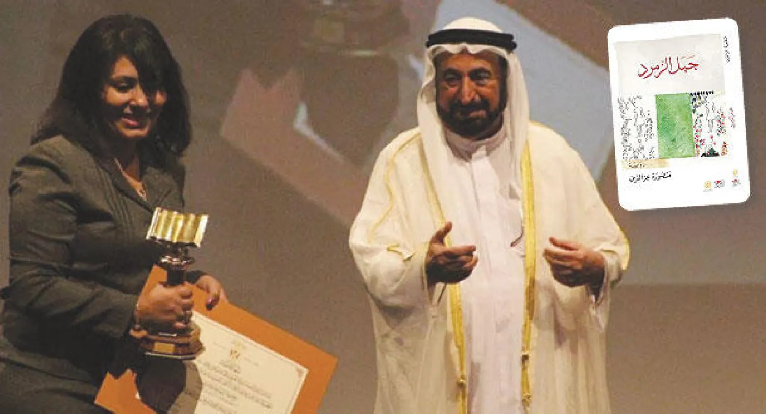 د. سلطان بن محمد القاسمي حاكم الشارقة مع الكاتبة منصورة عز الدين وفي الاطار غلاف الرواية