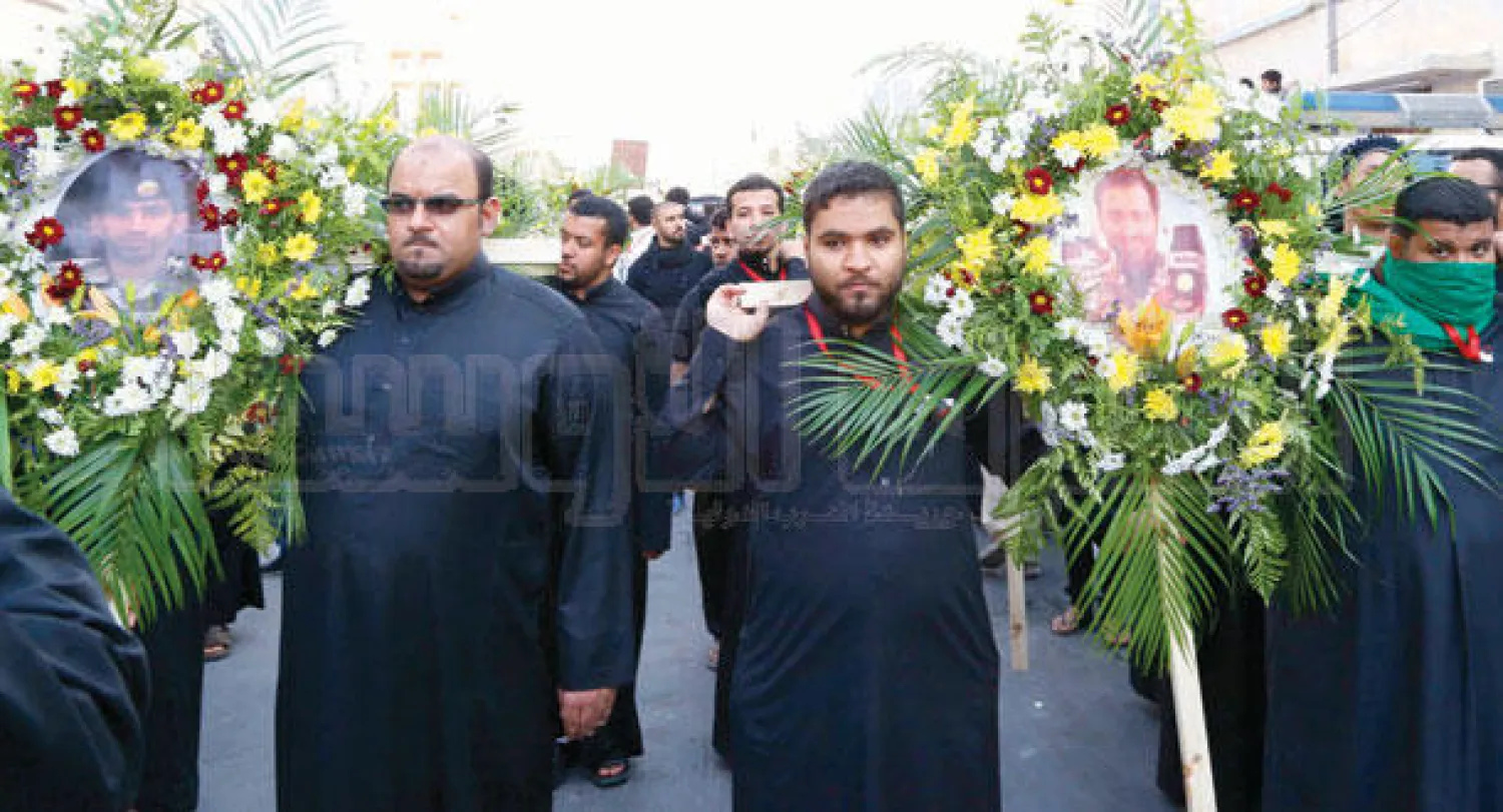 صورتا رجلي الأمن اللذين استشهدا في المواجهات الأمنية مع إرهابيي «دالوة» الأحساء محاطتان بأكاليل من الورد في مسيرة تشييع ضحايا الحادثة (تصوير:عيسى الدبيسي)