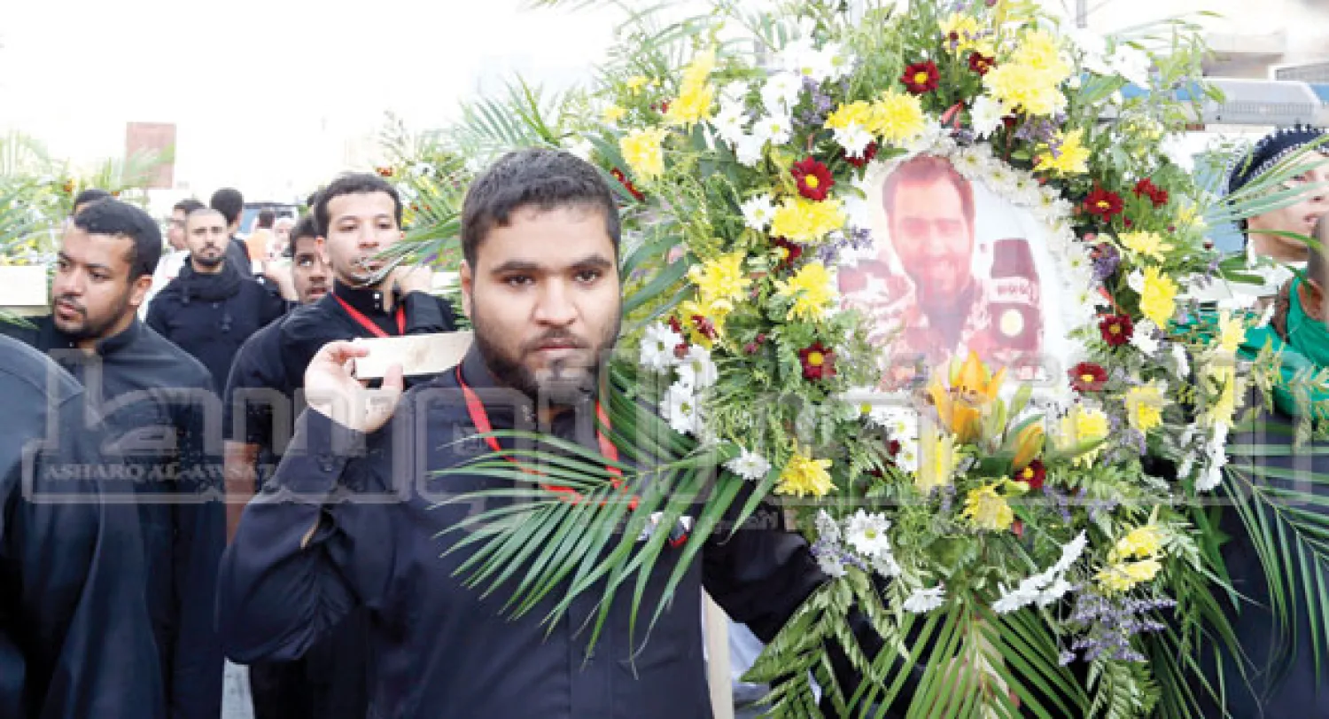 صورة شهيد الواجب تركي الرشيد محاطة بأكليل من الورد أثناء تشييع جثامين ضحايا حادثة «الدالوة» التي راح ضحيتها 7 من أبناء القرية (تصوير:عيسى الدبيسي)